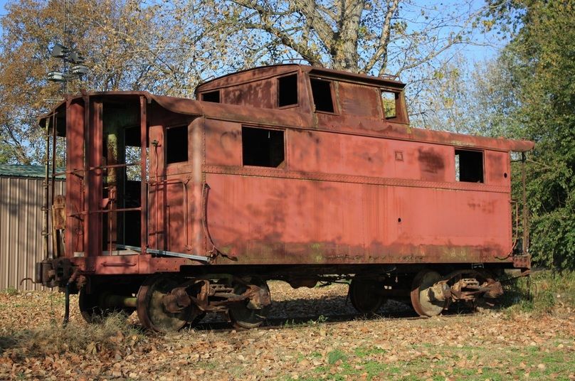 Image of an old, rusted caboose sitting in a yard. The Caboose was one of the places asbestos-containing material lurked.