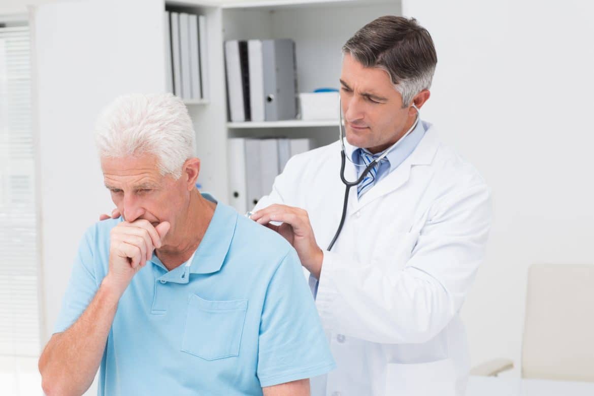 Image of a doctor checking an older man for signs of asbestos exposure in his lungs.